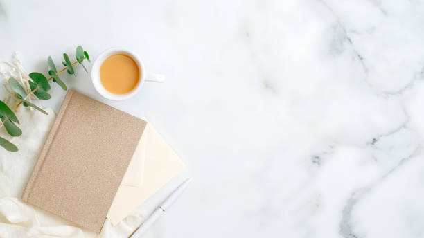 istock Paper notebook, cup of coffee, eucalyptus leaf, pen on marble background. Home office desk concept. Flat lay, top view, copy space. 1198740747