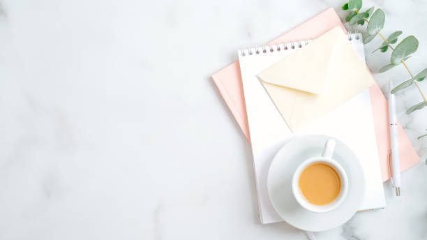 Feminine workspace with wedding to do list, envelope with love letter, pink notepad, cup of coffee, pen, eucalyptus leaf. Flat lay, top view. Wedding, bridal, marriage concept.