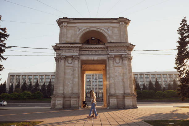 Triumphal Arch in Chisinau, Moldova In the city of Chisinau, the capital of Moldova, a young couple walks on Stefan cel Mare Boulevard past the Triumphal Arch, built in 1840 to commemorate the Russo-Turkish War. (September 9, 2016) chisinau photos stock pictures, royalty-free photos & images