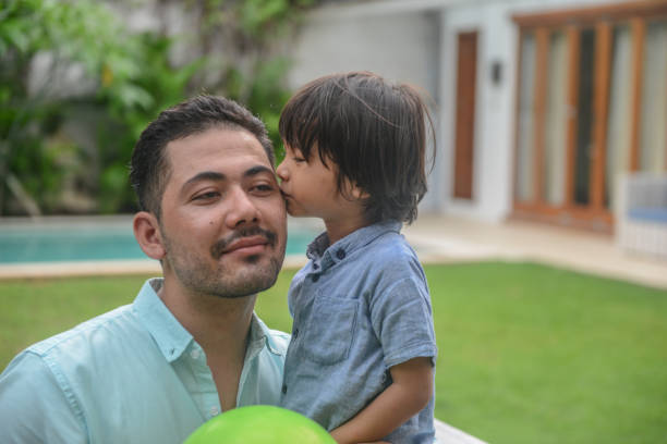 Close up of father and son look in eyes touch foreheads enjoy spending time together. Lifestyle photo of little boy and his bearded dad at home. Family value, father's love and support, father's day.