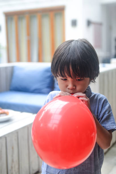 istock Asian little boy blowing balloon for Birthday Celebration 1198753531
