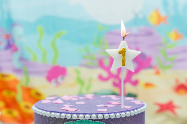 istock Lighted birthday candle in star shape with blurred background. 1 year anniversary, deep sea theme. Celebration, party and joy concept. 1198756104