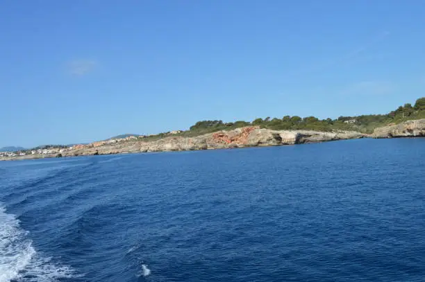 Photo of Inlet, blue water and rocky cliff. Mallorca sea and ocean. Boat exploration