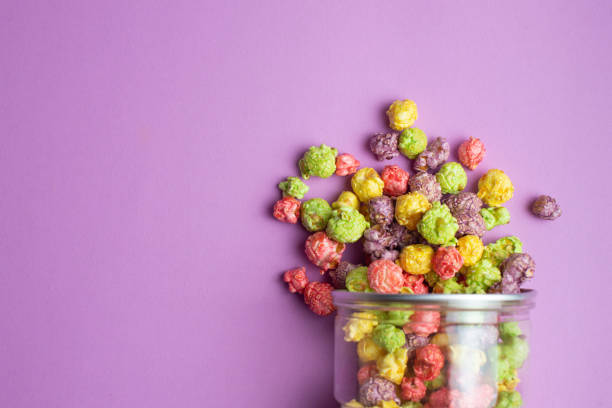 istock Multicolored fruit flavored popcorn in glass cups on pink background. Candy coated popcorn. 1198774390