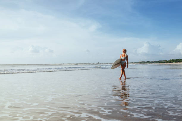 istock Surfer girl walking with board on the sandy beach. 1198776089