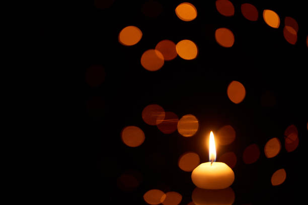 istock burning candle glowing in dark with bokeh lights on background 1198791101