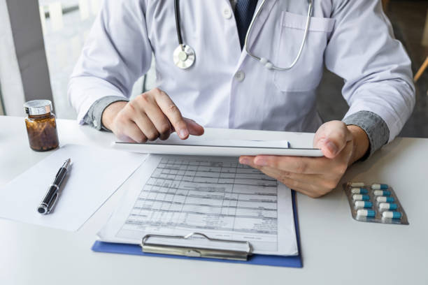 istock Doctor working and using digital tablet note information on paper report in hospital and medical stethoscope, medicine on clipboard on desk 1198791398