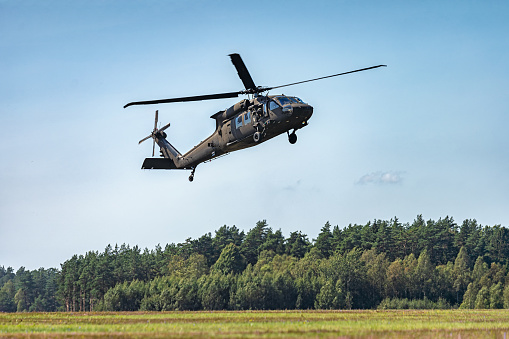 Picture of Military helicopter flying in the sky with forest at the background