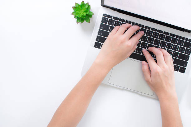 istock Human hands on a modern style white desk with a laptop computer top view. 1198793894