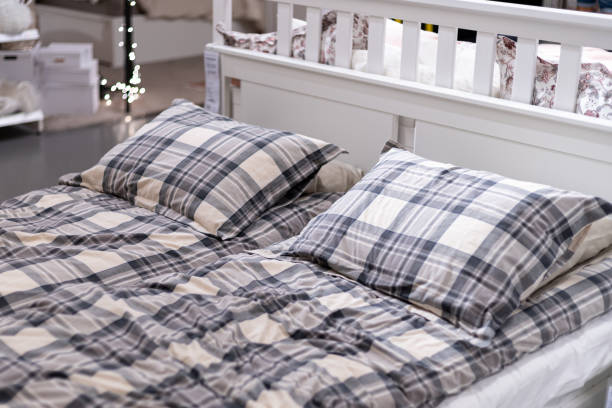 istock Lovely bedroom interior with soft beige walls framing double bed covered in gray checked bedding 1198793917