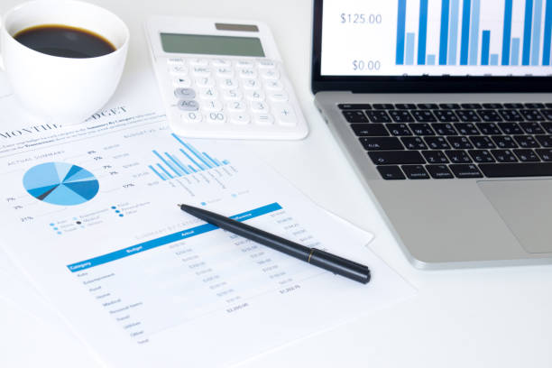 istock Side view of laptop computer, business worker on a modern style white desk. With documents and financial graph screen. 1198794072