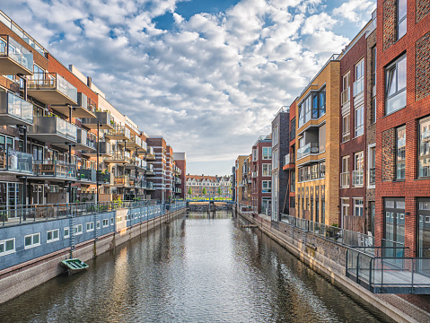 Image of Colorful apartments on the both sides of canal in Amsterdam with boats and blue sky