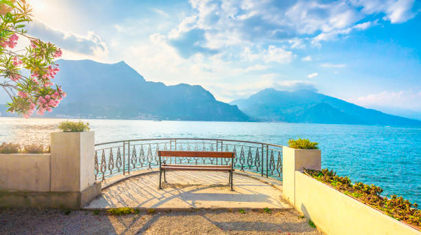 скамейка на берегу озера в пейзаже озера комо. белладжио италия - lake como water italy sunset стоковые фото и изображения