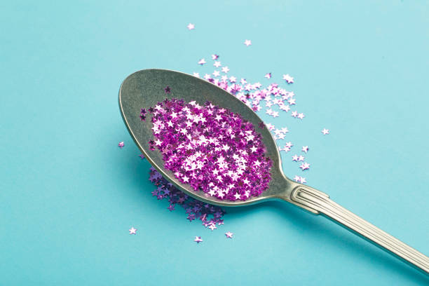 Glitter in a spoon on blue background. Celebration, party, birthday magic background. Creative minimal art concept