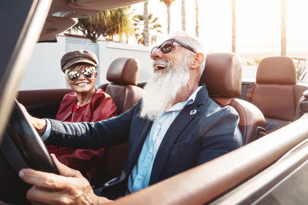 glückliches seniorenpaar mit spaß am neuen cabrio - reife menschen genießen die zeit zusammen während der roadtrip urlaub - senioren-lifestyle und reise-transport-konzept - couple men fashion luxury stock-fotos und bilder