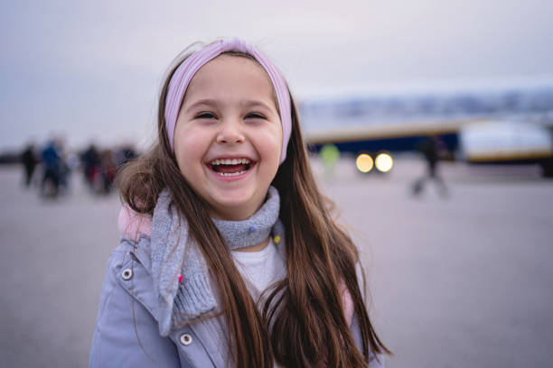飛行機旅行の後にカメラを見て歯の笑顔の小さな女の子 - child little girls shy standing ストックフォトと画像