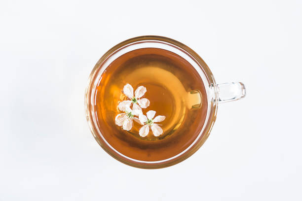 Cup of tea with cherry flowers top view on a white background