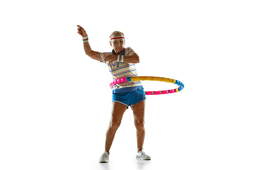 Senior woman wearing sportwear training with hoop on white background. Caucasian female model in great shape stays active. Concept of sport, activity, movement, wellbeing, confidence. Copyspace.