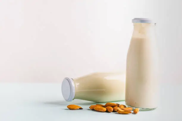 Photo of Almond nut milk drink in glass bottles light background. The concept of diet healthy eating. Horizontal frame copy space