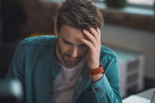 istock Handsome sad young man touching his head 1198814258