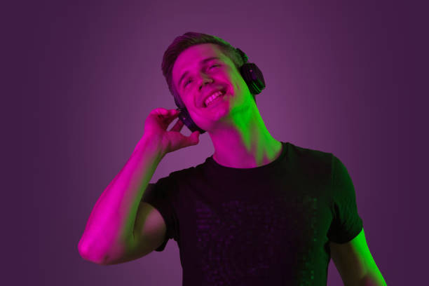 istock Caucasian man's portrait isolated on purple studio background in neon light 1198816546