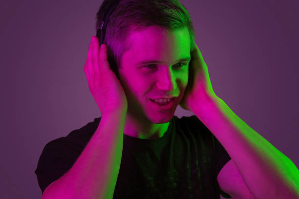 istock Caucasian man's portrait isolated on purple studio background in neon light 1198816574