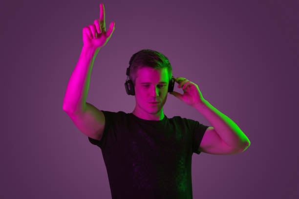 istock Caucasian man's portrait isolated on purple studio background in neon light 1198816587
