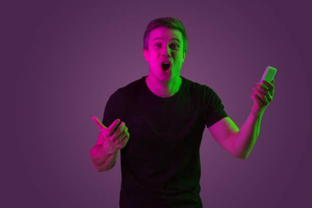 istock Caucasian man's portrait isolated on purple studio background in neon light 1198816779