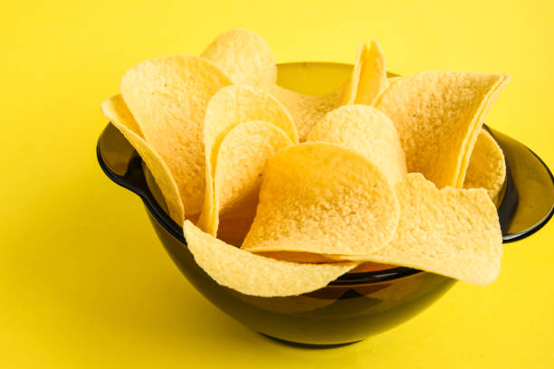 istock Delicious Crispy potato chips in bowl on yellow background 1198827051