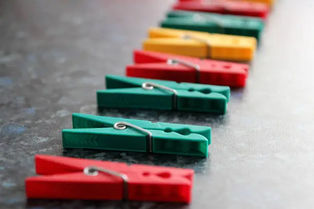 Green, red and yellow plastic clothespins. Color linen clothespins in row. Selective focus.