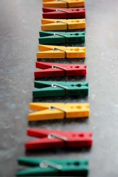 Color linen clothespins in row. Green, red and yellow plastic clothespins. Selective focus.