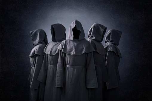 Grupo de cinco figuras de miedo en capas encapuchadas en la oscuridad photo