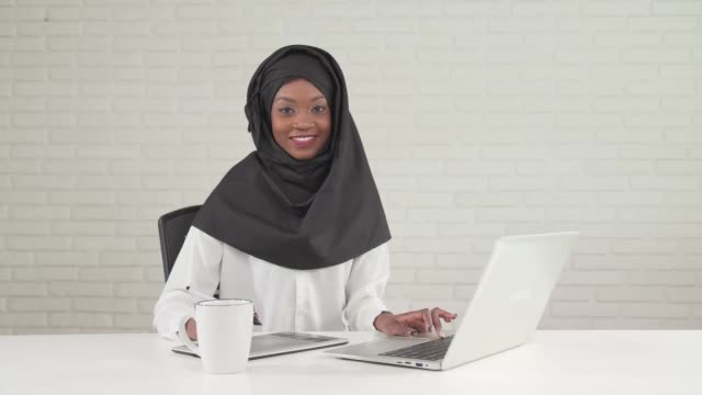 Smiling woman typing on laptop.