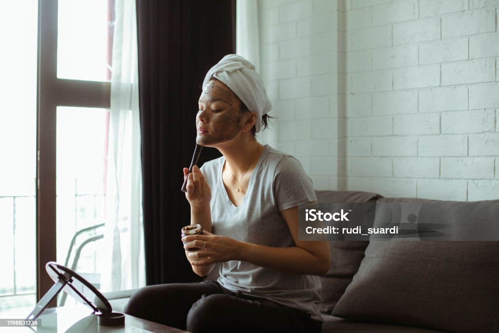 Attractive Young Woman Wrapped with Bath Towels and cream mask on the face Domestic Life Stock Photo