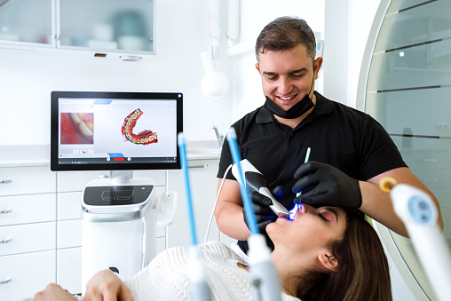 Dentista escaneando los dientes del paciente con un escáner CEREC photo