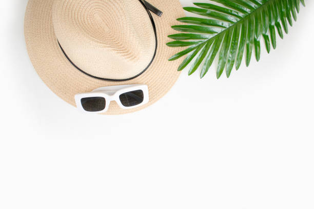 istock Sunglasses on a beach hat with leaves and white background. Top view and copy space. 1198843036