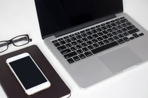 istock Modern white office desk with computers, notebooks and smartphones for business people. Side view. 1198843201
