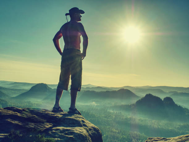 istock Tall man in shorts wearing a cowboy hat shielding his face 1198844258
