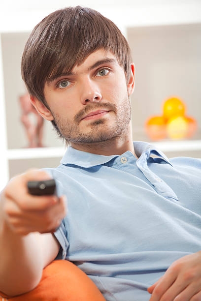 istock man with television remote at home 119884482
