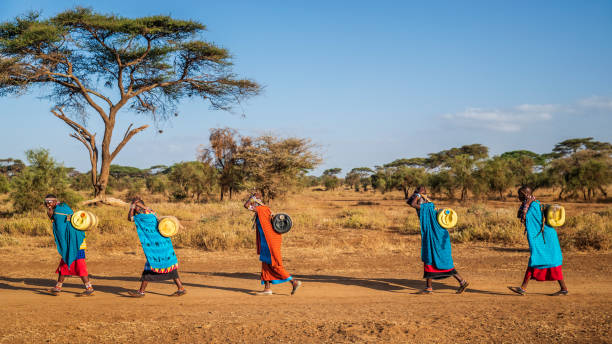 afrikaanse vrouwen uit maasai stam dragen water, kenia, oost-afrika - landschap dorp stockfoto's en -beelden