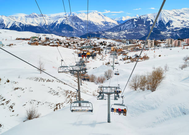 blick von einem skisessellift, der den berg hinauffährt, im winter, über dem bergdorf la toussuire, teil des ski-skigebiets les sybelles, frankreich. - ski slope overhead cable car snow frost stock-fotos und bilder