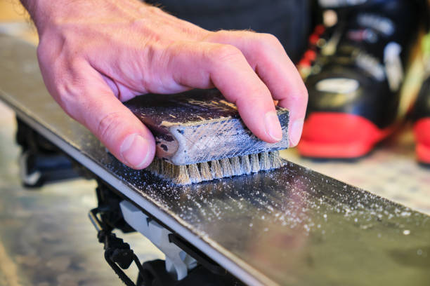 main mâle utilisant une brosse en laiton pour nettoyer la structure d'une base de ski. outil de tuning et d'entretien de ski. - tourist resort audio photos et images de collection