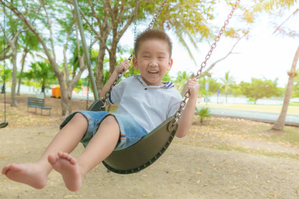 istock Smiling boy playing happiness on a swing with playground. 1198852160