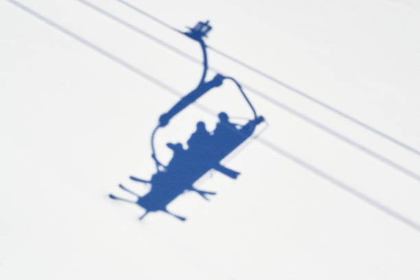 Shadow of skiers in a chairlift in Winter, high above a ski slope in Serre Chevalier ski domain, France, on a sunny day. Shadow of skiers in a chairlift in Winter, high above a ski slope in Serre Chevalier ski domain, France, on a sunny day. public domain photos stock pictures, royalty-free photos & images