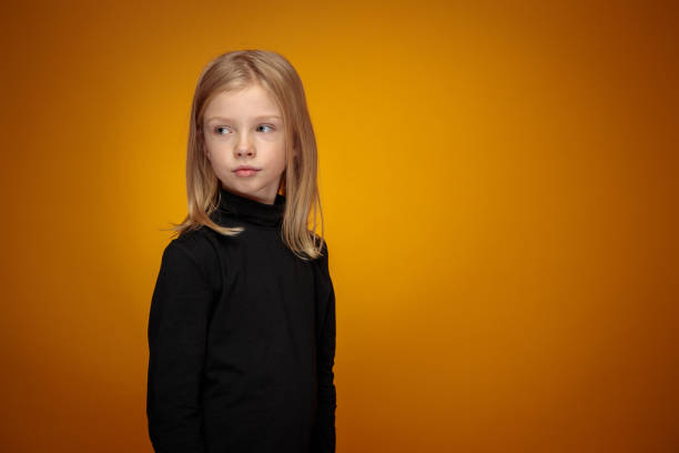 three-quarter portrait of pensive little blond girl in black stock photo