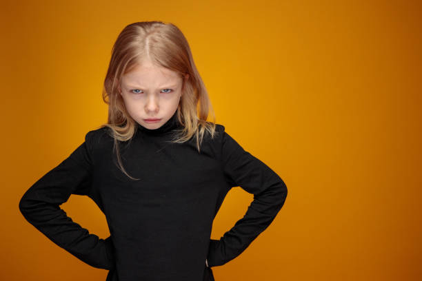 angry displeased little girl in black with long blond hair stock photo