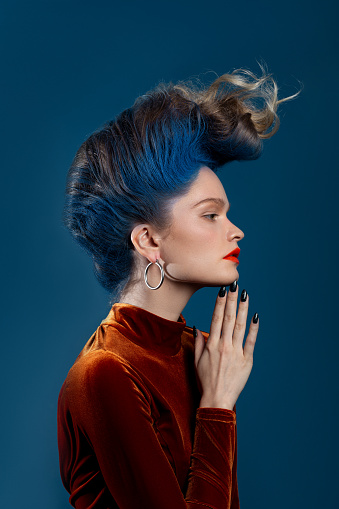 Young woman with blue mohawk wearing orange velvet dress