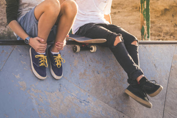 z bliska dwóch młodych chłopców siedzących na rampie half pipe, po ładnych sztuczkach i skokach w skateparku. modne nastolatki korzystające z wolnego czasu w skate parku. koncepcja młodości, współpracy i przyjaźni. - skateboarding skateboard teenager child zdjęcia i obrazy z banku zdjęć