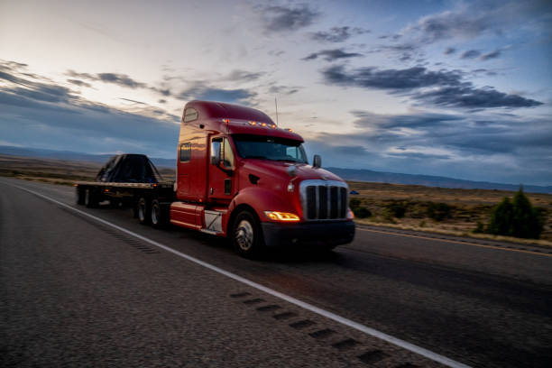 flat bed long haul semi truck speeding down a four lane highway to delivery their loads - flatbed truck imagens e fotografias de stock