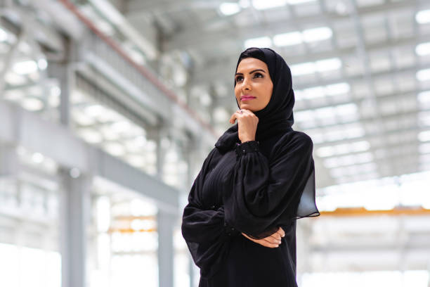 Portrait of Contemplative Middle Eastern Design Professional Low angle close-up of female construction professional in traditional Islamic clothing with hand on chin and observing development of Abu Dhabi site. emirati culture photos stock pictures, royalty-free photos & images
